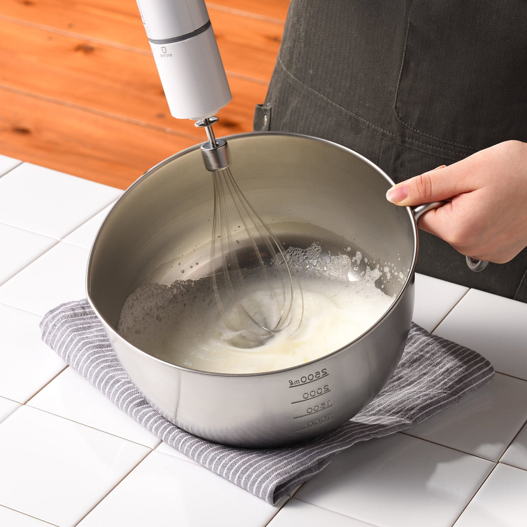 Person holding an AUX Japanese Stainless Steel Mixing Bowl with Handle while whipping egg whites with an electric mixer