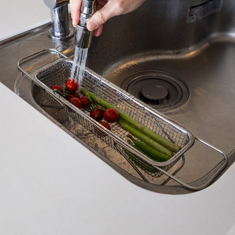 Nami washing fresh tomatoes and asparagus inside adjustable stainless steel draining rack expandable over sink colander