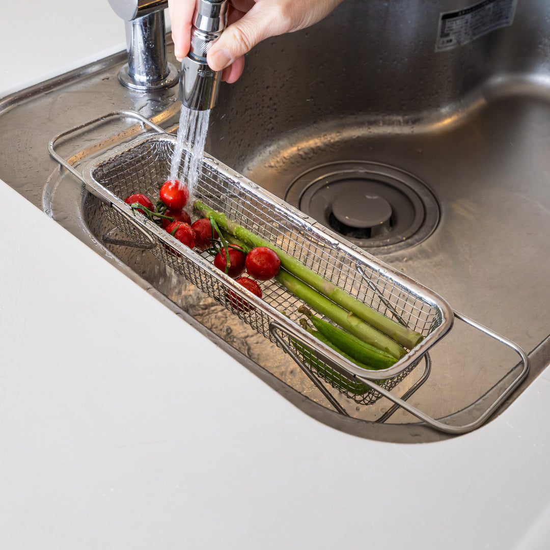 Nami washing fresh tomatoes and asparagus inside adjustable stainless steel draining rack expandable over sink colander