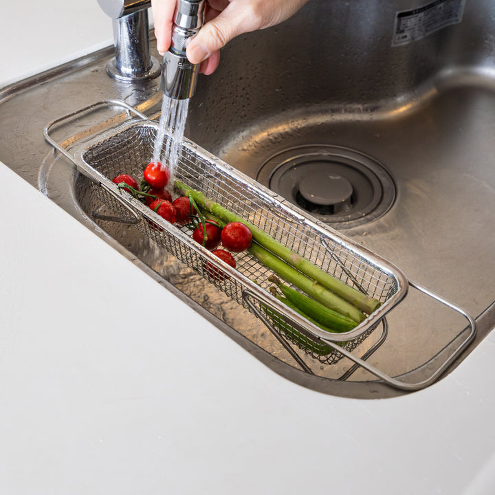 Nami washing fresh tomatoes and asparagus inside adjustable stainless steel draining rack expandable over sink colander