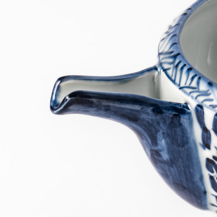 Porcelain sake pourer with spout featuring hand-painted indigo landscape and arabesque patterns in a traditional Japanese style.