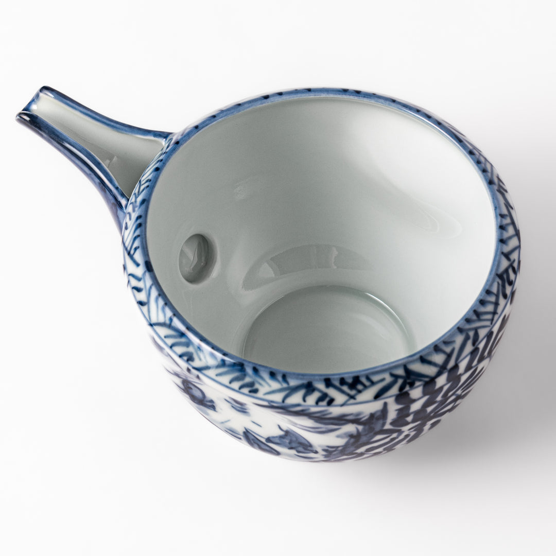 Porcelain sake pourer with spout featuring hand-painted indigo landscape and arabesque patterns in a traditional Japanese style.