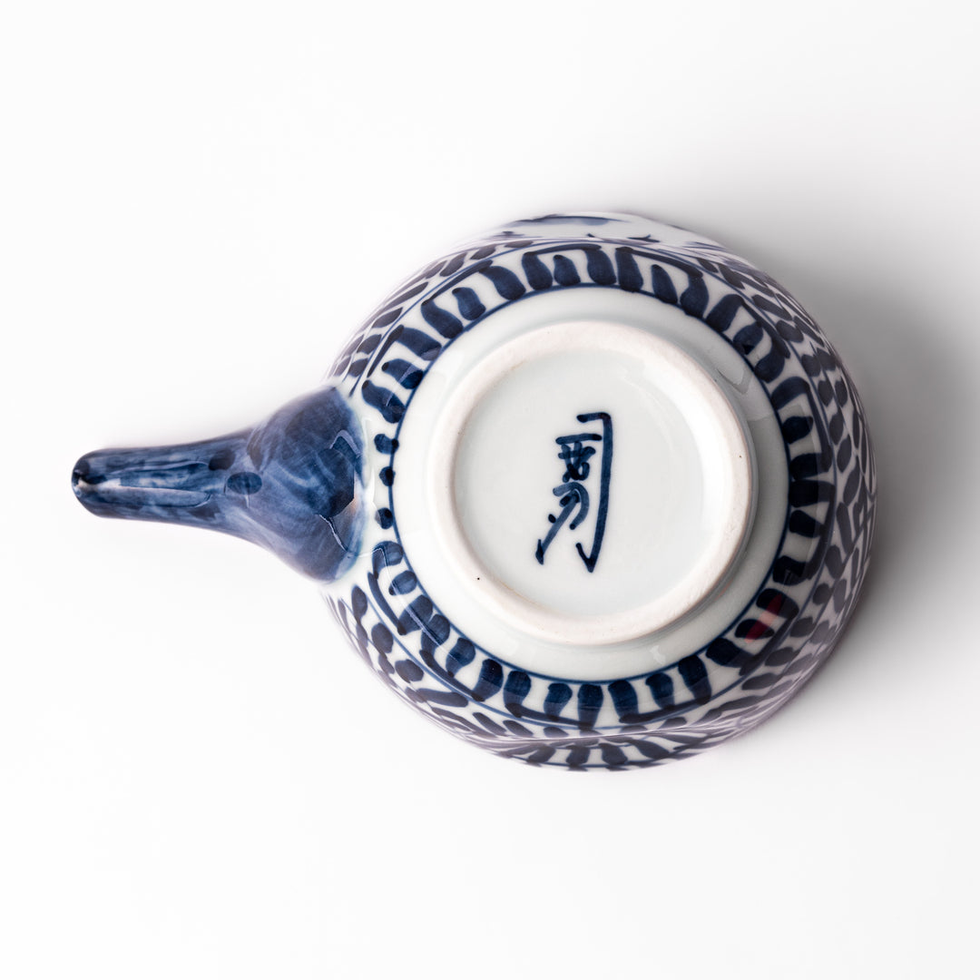 Porcelain sake pourer with spout featuring hand-painted indigo landscape and arabesque patterns in a traditional Japanese style.