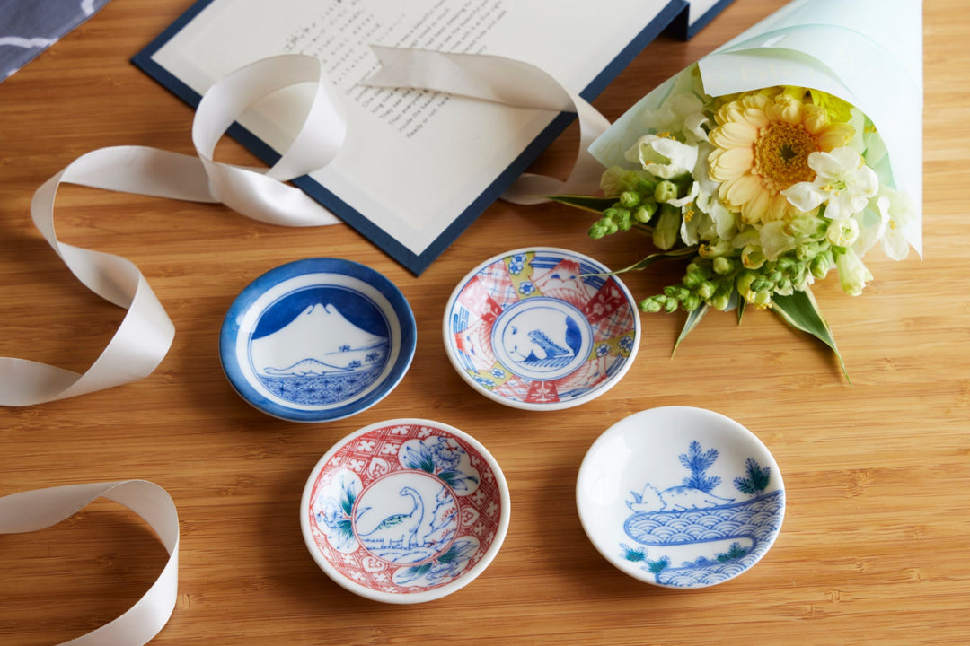 Japanese porcelain small plates with traditional blue and red motifs arranged with flowers and ribbon on a wooden table