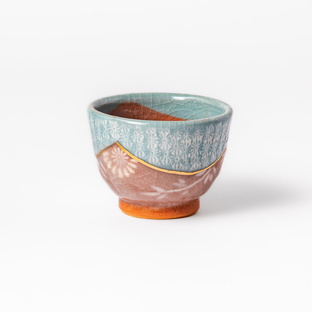 Ceramic tea cup featuring a crackled turquoise glaze with floral patterns and a contrasting earthy brown base for a handcrafted look.