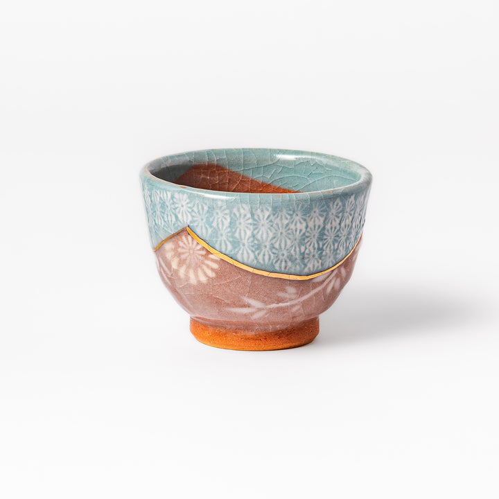 Ceramic tea cup featuring a crackled turquoise glaze with floral patterns and a contrasting earthy brown base for a handcrafted look.