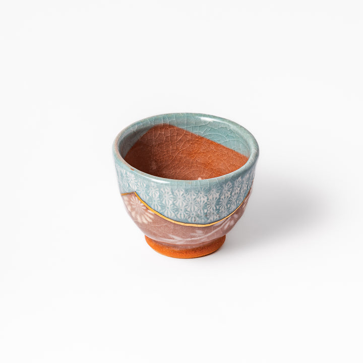 Ceramic tea cup featuring a crackled turquoise glaze with floral patterns and a contrasting earthy brown base for a handcrafted look.