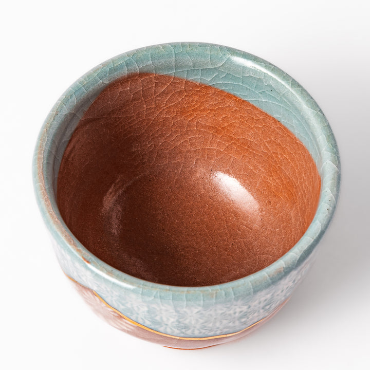 Ceramic tea cup featuring a crackled turquoise glaze with floral patterns and a contrasting earthy brown base for a handcrafted look.