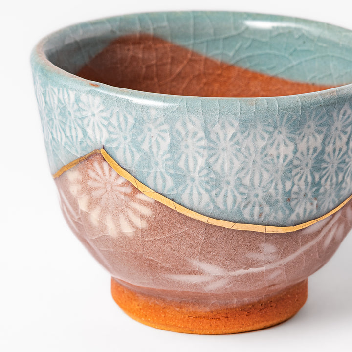 Ceramic tea cup featuring a crackled turquoise glaze with floral patterns and a contrasting earthy brown base for a handcrafted look.