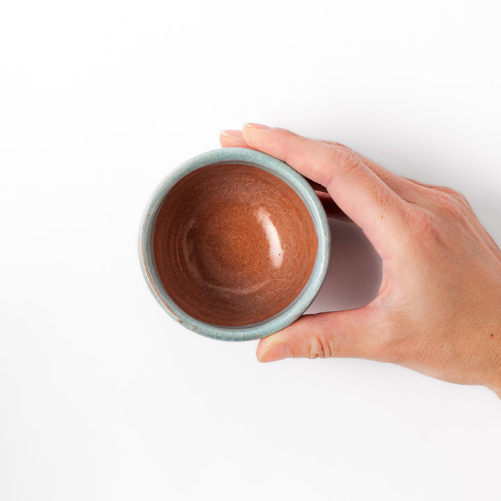 Ceramic tea cup featuring a crackled turquoise glaze with floral patterns and a contrasting earthy brown base for a handcrafted look.