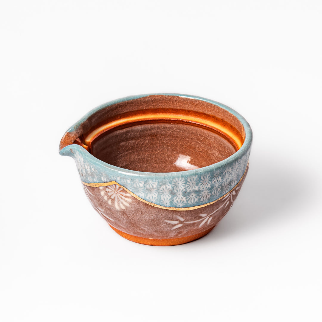 Ceramic teapot with lid featuring a turquoise crackle glaze and floral patterns in soft brown tones accented by a curved gold line.