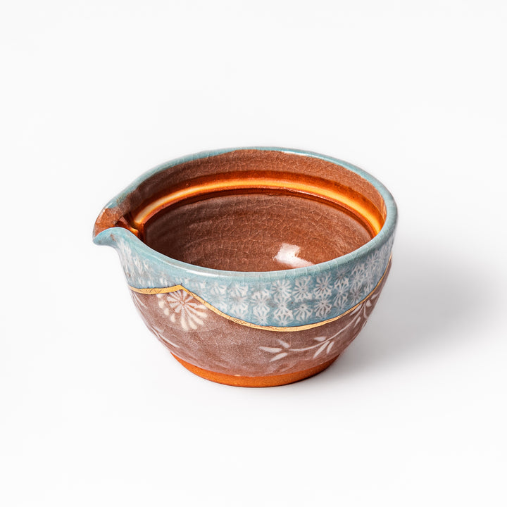 Ceramic teapot with lid featuring a turquoise crackle glaze and floral patterns in soft brown tones accented by a curved gold line.