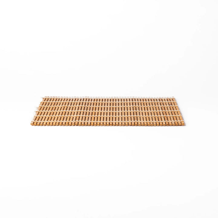 Traditional bamboo sushi rolling mat with uniform slats and white cotton string, partially rolled to show flexibility for making perfect sushi at home.