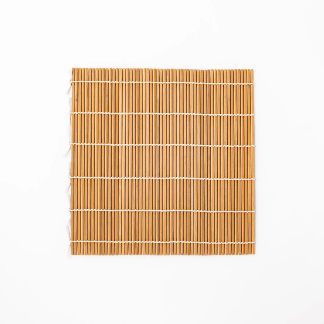 Bamboo sushi rolling mat with smooth, evenly spaced slats and white cotton string, perfect for shaping homemade sushi rolls with traditional style.
