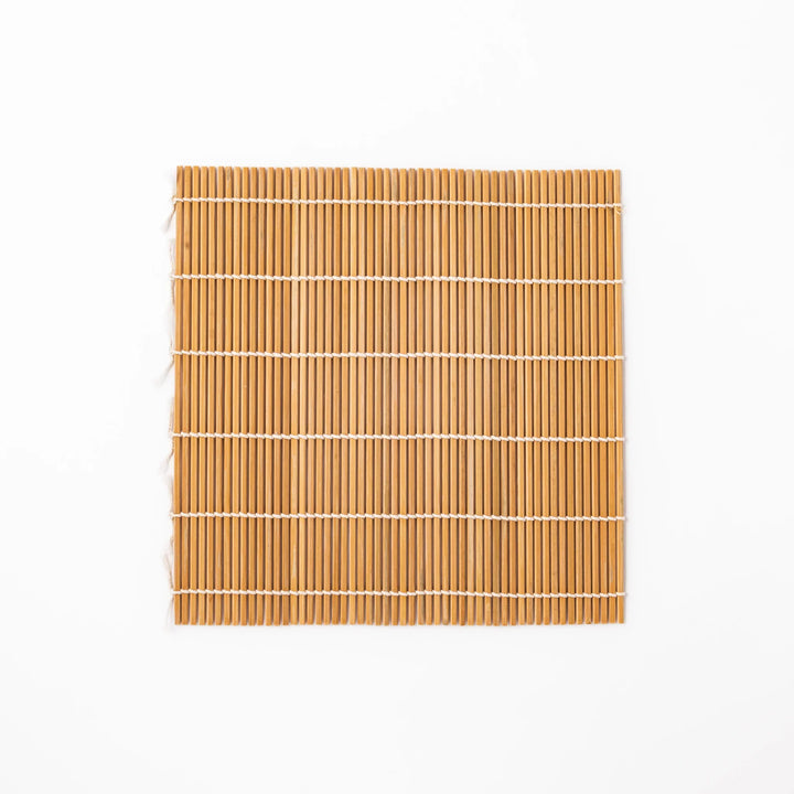 Bamboo sushi rolling mat with smooth, evenly spaced slats and white cotton string, perfect for shaping homemade sushi rolls with traditional style.
