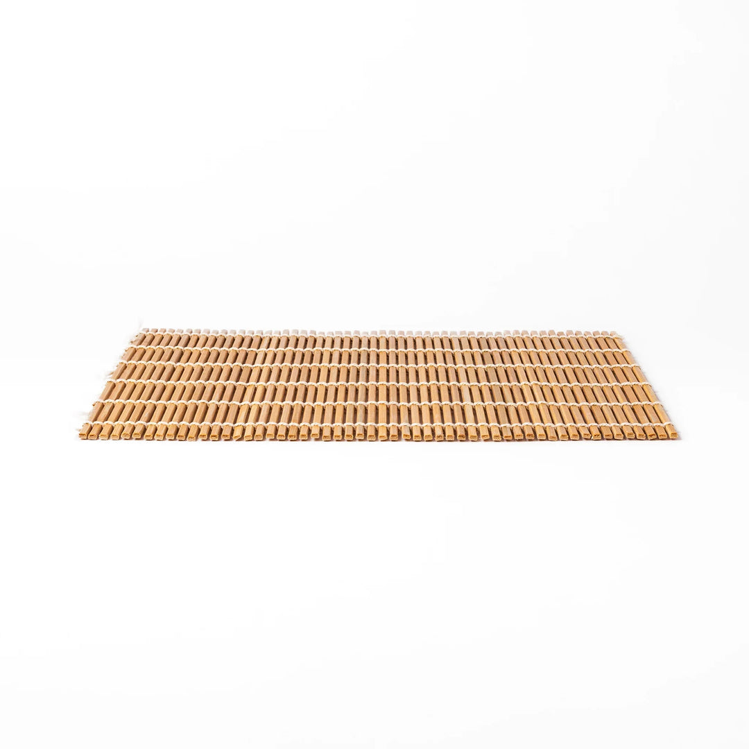 Bamboo sushi rolling mat with smooth, evenly spaced slats and white cotton string, perfect for shaping homemade sushi rolls with traditional style.
