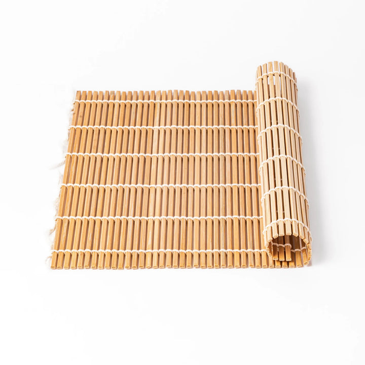 Bamboo sushi rolling mat with smooth, evenly spaced slats and white cotton string, perfect for shaping homemade sushi rolls with traditional style.

