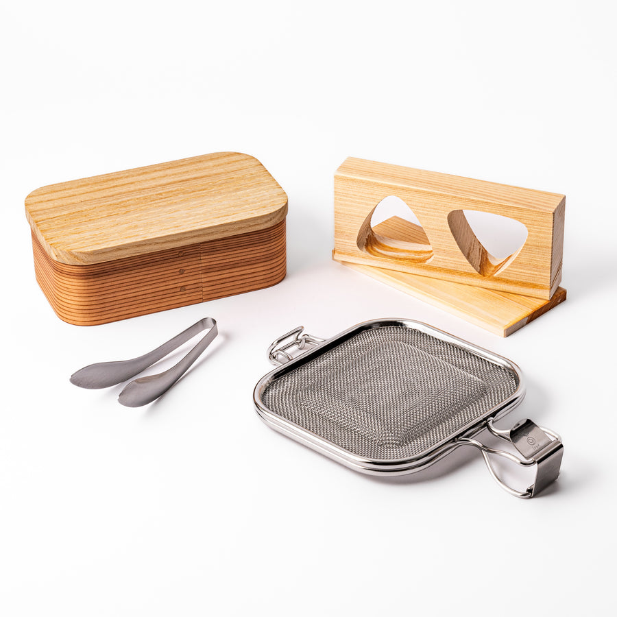 Japanese bento set featuring a wooden lunch box, onigiri mold, stainless steel grilling mesh, and mini tongs, perfect for crafting beautiful homemade lunches with ease.