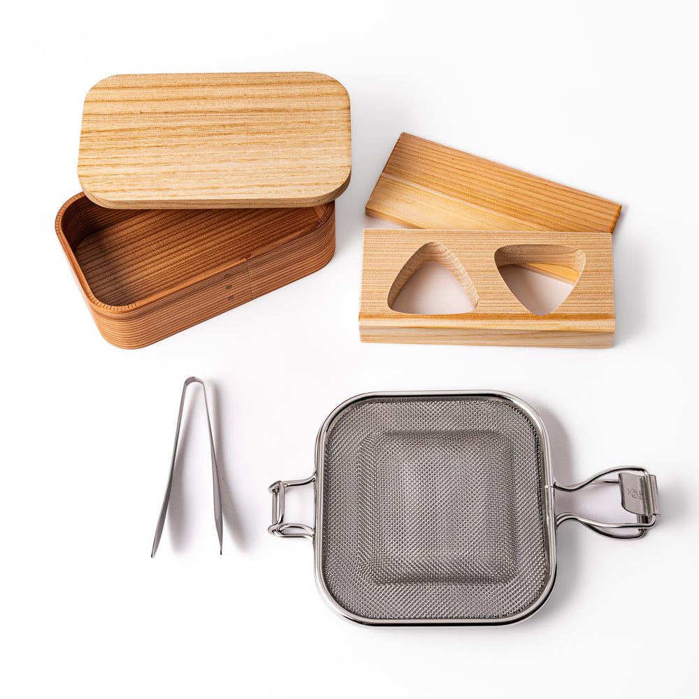 Japanese bento set featuring a wooden lunch box, onigiri mold, stainless steel grilling mesh, and mini tongs, perfect for crafting beautiful homemade lunches with ease.