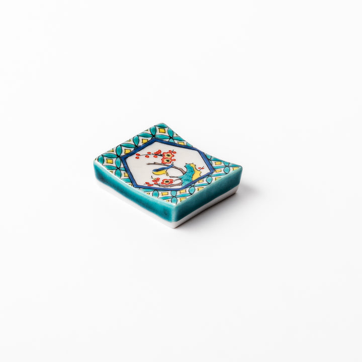 Rectangular Japanese ceramic chopstick rest with turquoise border and central motif of bird on plum blossoms in vivid colors.