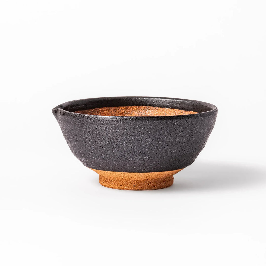 Black ceramic suribachi mortar bowl with rough-textured brown interior grooves and spout, ideal for grinding sesame seeds and other seasonings with precision.