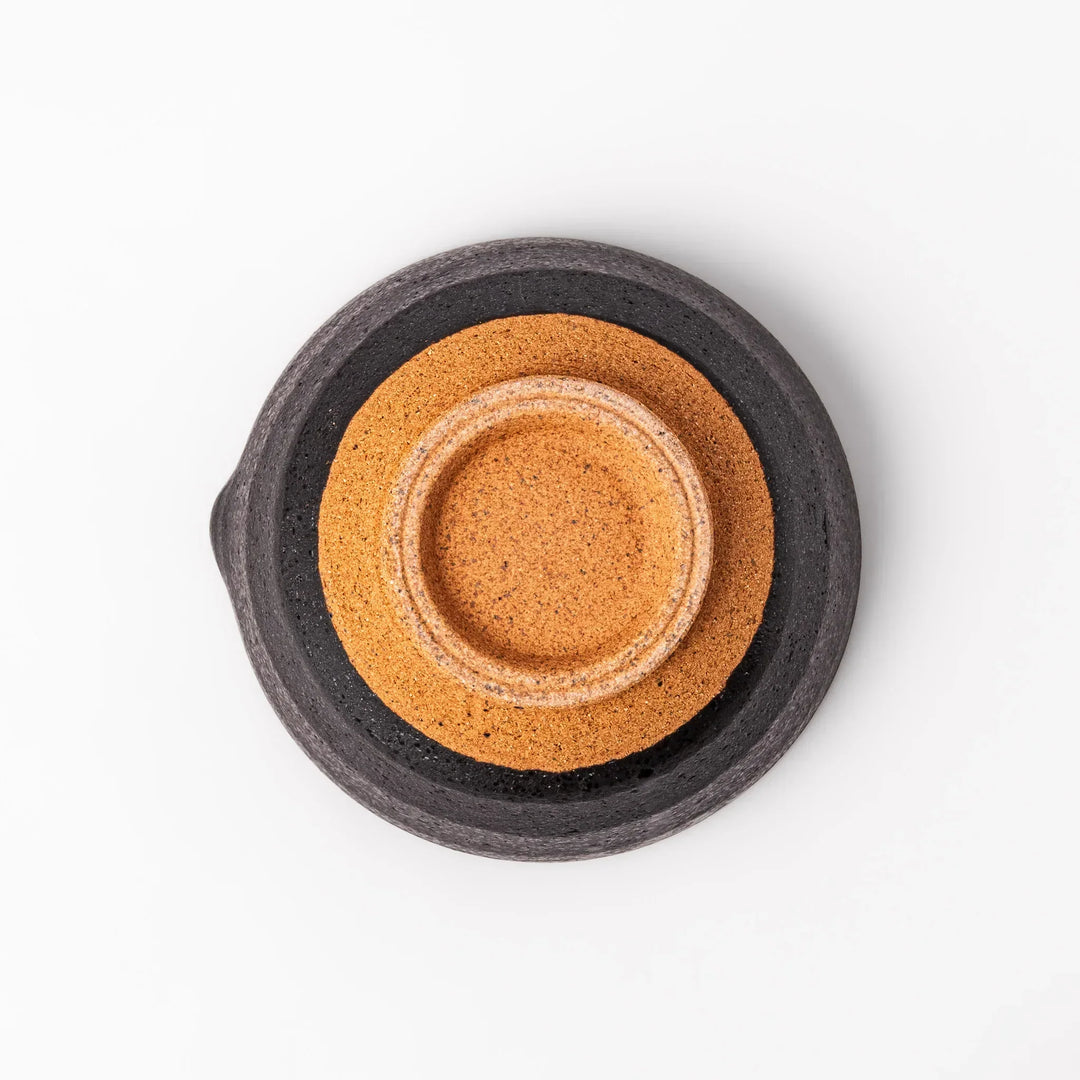 Black ceramic suribachi mortar bowl with rough-textured brown interior grooves and spout, ideal for grinding sesame seeds and other seasonings with precision.