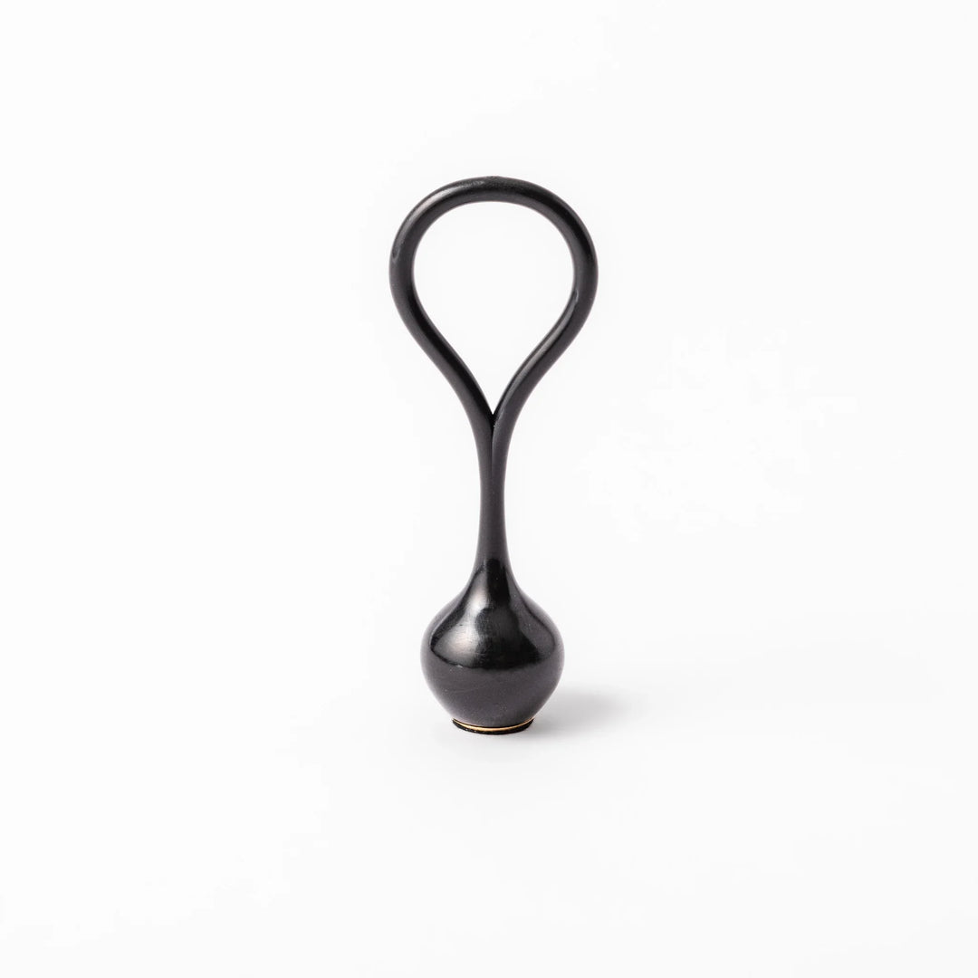 Black meditation bowl striker with looped handle and felt tip for gentle resonant sounds in prayer rituals.