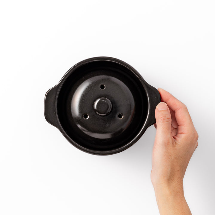 Black ceramic microwave rice cooker with double lid and side handles, designed for convenient cooking and serving at the table.