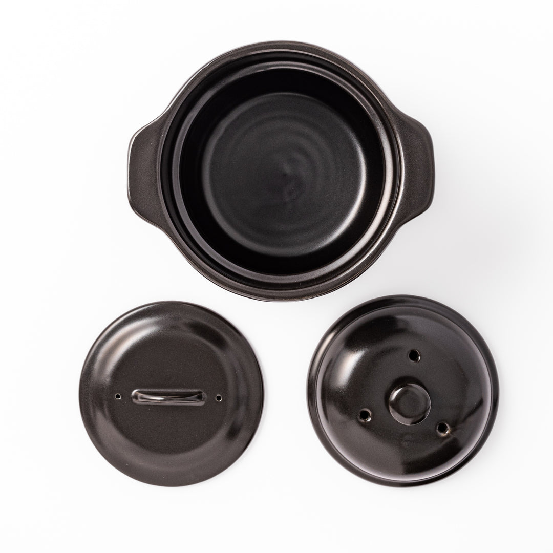 Black ceramic microwave rice cooker with double lid and side handles, designed for convenient cooking and serving at the table.