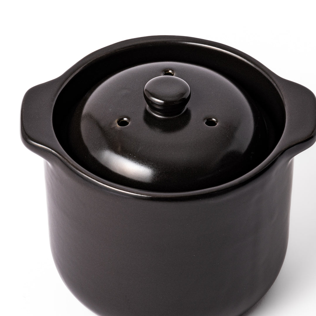 Black ceramic microwave rice cooker with double lid and side handles, designed for convenient cooking and serving at the table.