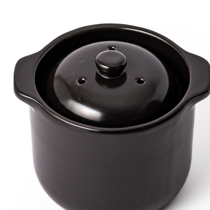 Black ceramic microwave rice cooker with double lid and side handles, designed for convenient cooking and serving at the table.
