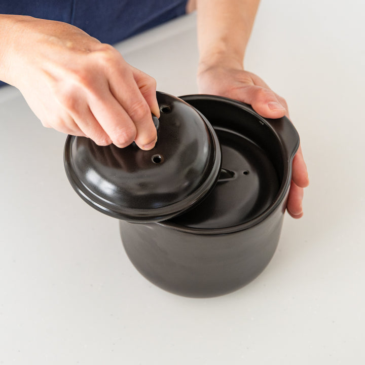 Black microwave rice cooker with double lid showing inner vented lid and steam holes