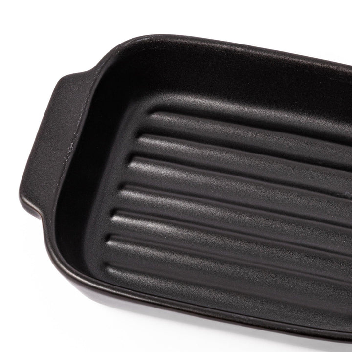 Rectangular black ceramic baking dish with ridged base and side handle, designed for oven use and versatile table presentation.