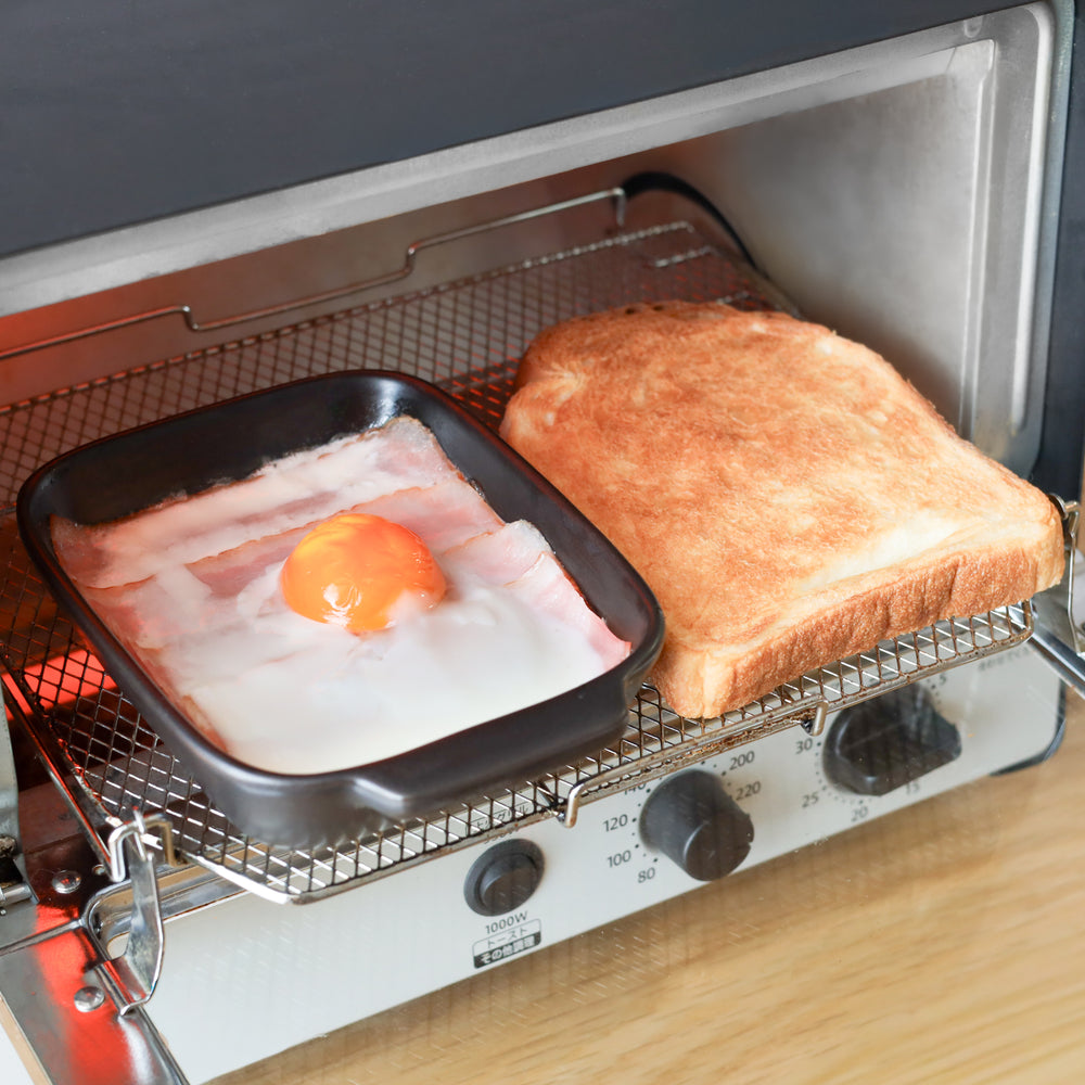 Black Wave Baking Dish in toaster oven cooking bacon and egg, shown beside golden toast, perfect for quick Japanese breakfast.