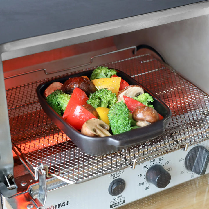 Black Wave Baking Dish in toaster oven filled with broccoli, bell peppers, and mushrooms, perfect for roasting and everyday cooking.