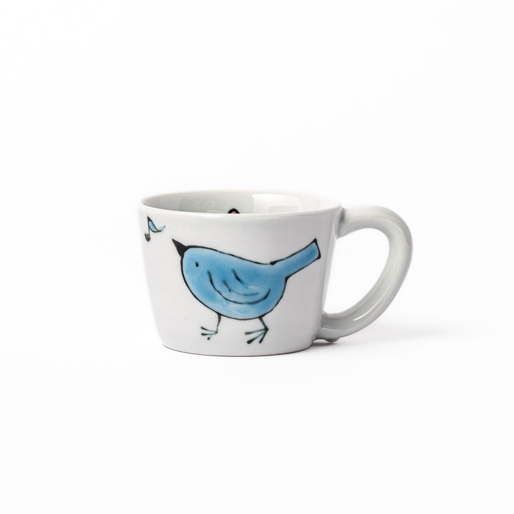 Japanese children’s mug featuring a hand-painted blue bird and musical note design on white porcelain, crafted for little hands to enjoy warm drinks with joy.