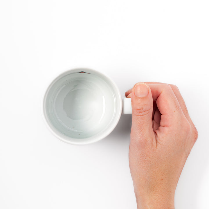 Japanese children’s mug featuring a hand-painted blue bird and musical note design on white porcelain, crafted for little hands to enjoy warm drinks with joy.