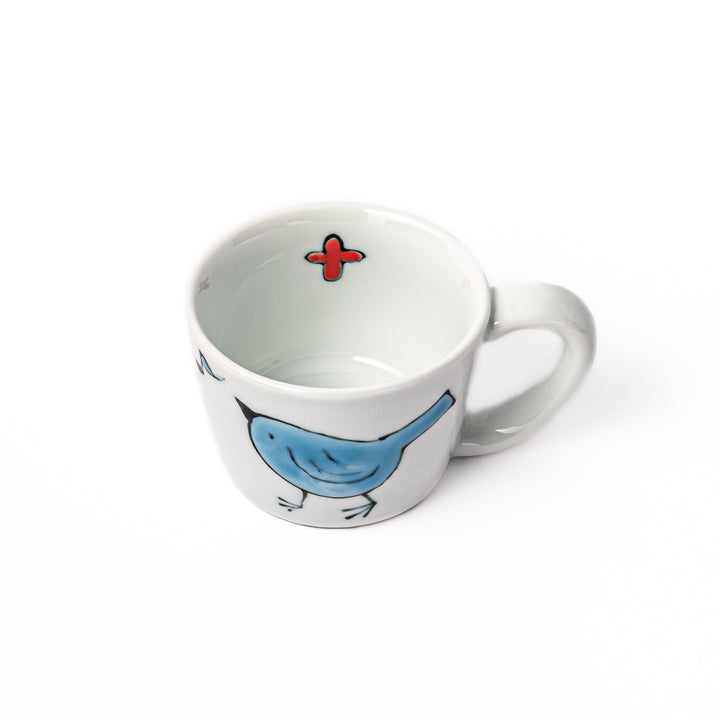 Japanese children’s mug featuring a hand-painted blue bird and musical note design on white porcelain, crafted for little hands to enjoy warm drinks with joy.