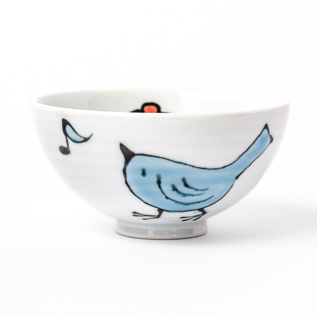 Japanese children’s rice bowl featuring a hand-painted blue bird and musical note motif on white porcelain, designed to bring a cheerful touch to everyday meals.