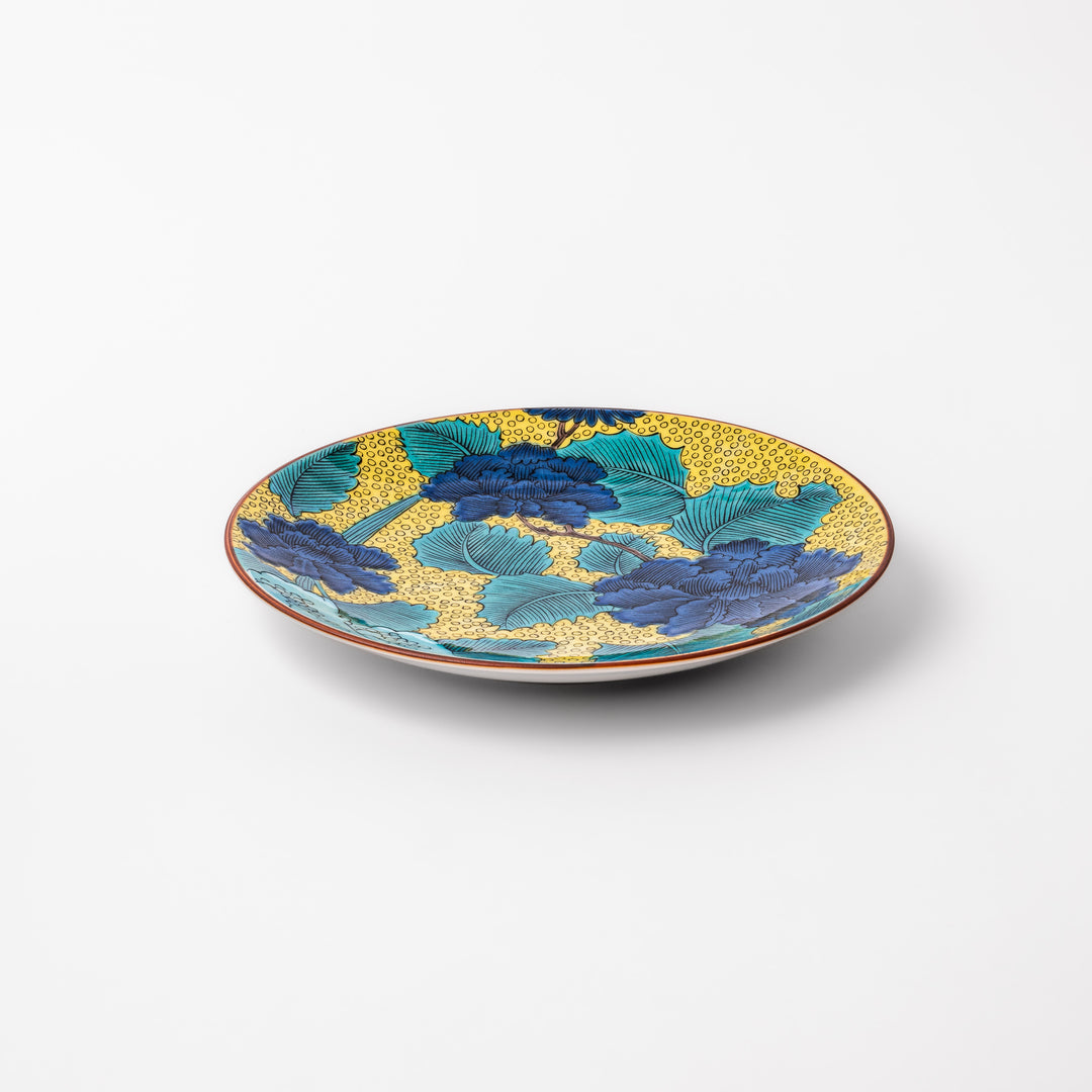 Porcelain dessert plate with bold blue peony flowers, green leaves, and a golden yellow background accented by intricate dot patterns.