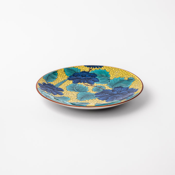 Porcelain dessert plate with bold blue peony flowers, green leaves, and a golden yellow background accented by intricate dot patterns.