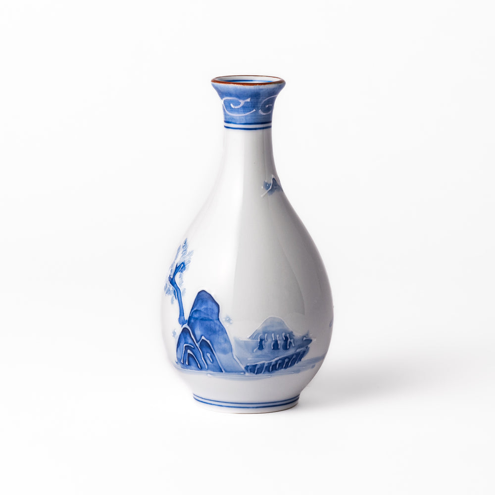 Porcelain sake flask with hand-painted blue mountain and village scenery, featuring a red rim and elegant traditional silhouette.