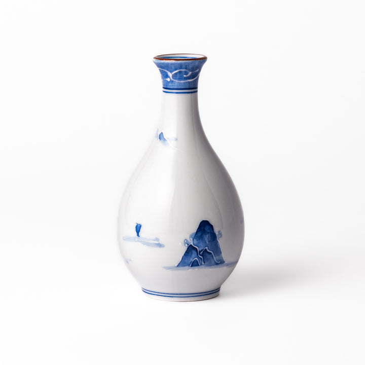 Porcelain sake flask with hand-painted blue mountain and village scenery, featuring a red rim and elegant traditional silhouette.