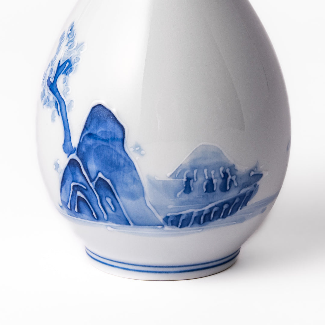 Porcelain sake flask with hand-painted blue mountain and village scenery, featuring a red rim and elegant traditional silhouette.