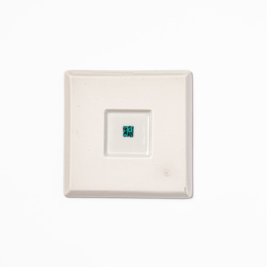 Square blue Japanese ceramic coaster with delicate white sakura blossoms and scattered petals, perfect for traditional dining settings.