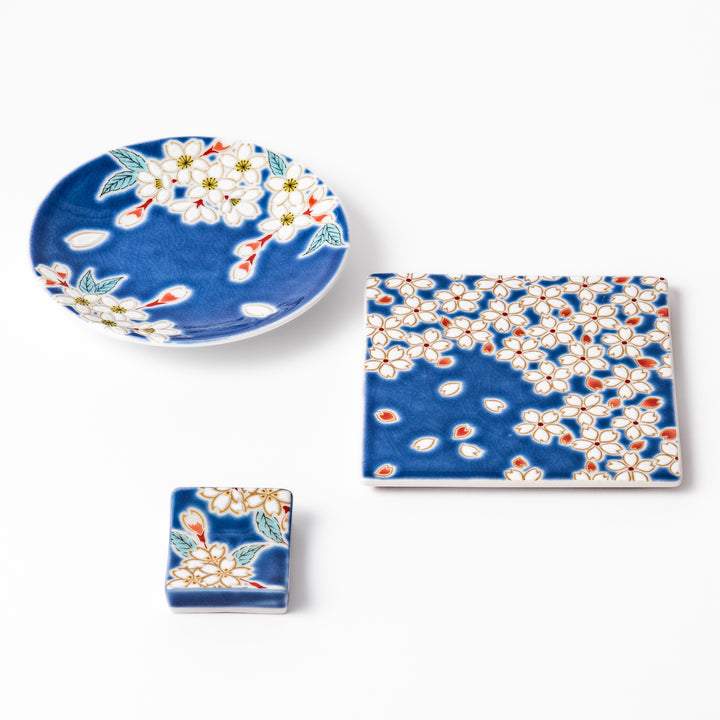Japanese ceramic set featuring blue dishes and chopstick rest decorated with delicate white sakura blossoms, perfect for elegant traditional dining.