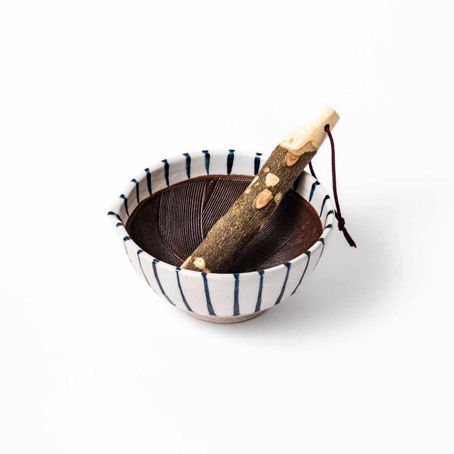 Blue-striped ceramic suribachi mortar with grooved brown interior and rustic wooden pestle, ideal for grinding sesame seeds and traditional Japanese spices.