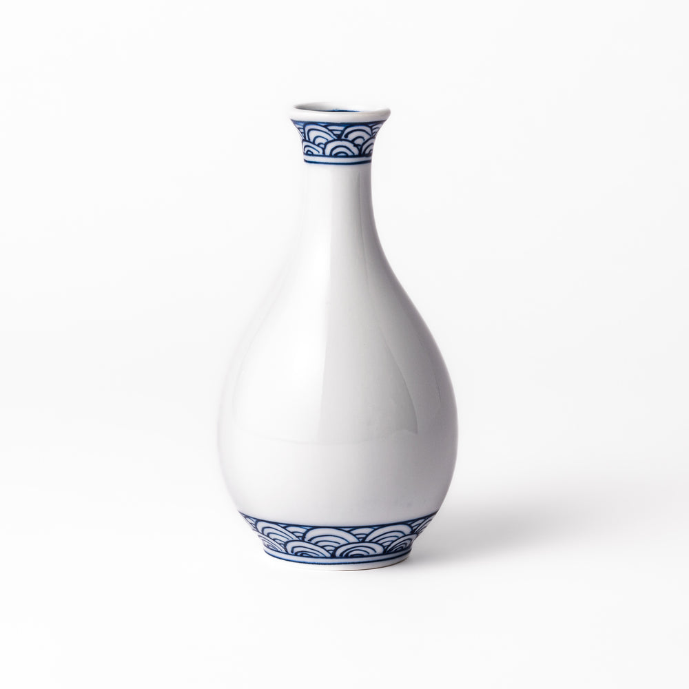 Porcelain sake flask with a smooth white body accented by traditional blue seigaiha wave patterns around the neck and base.