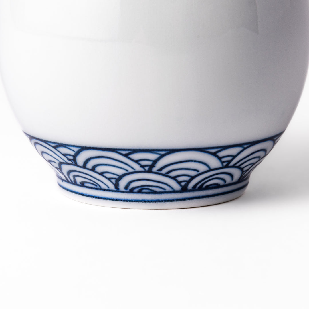 Porcelain sake flask with a smooth white body accented by traditional blue seigaiha wave patterns around the neck and base.