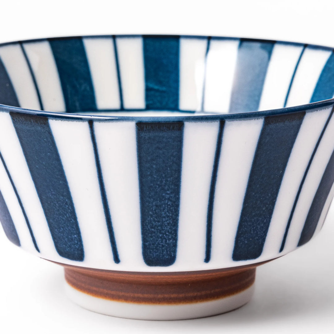 Japanese porcelain rice bowl with bold indigo and white stripe pattern and terracotta base, crafted in modern traditional style.